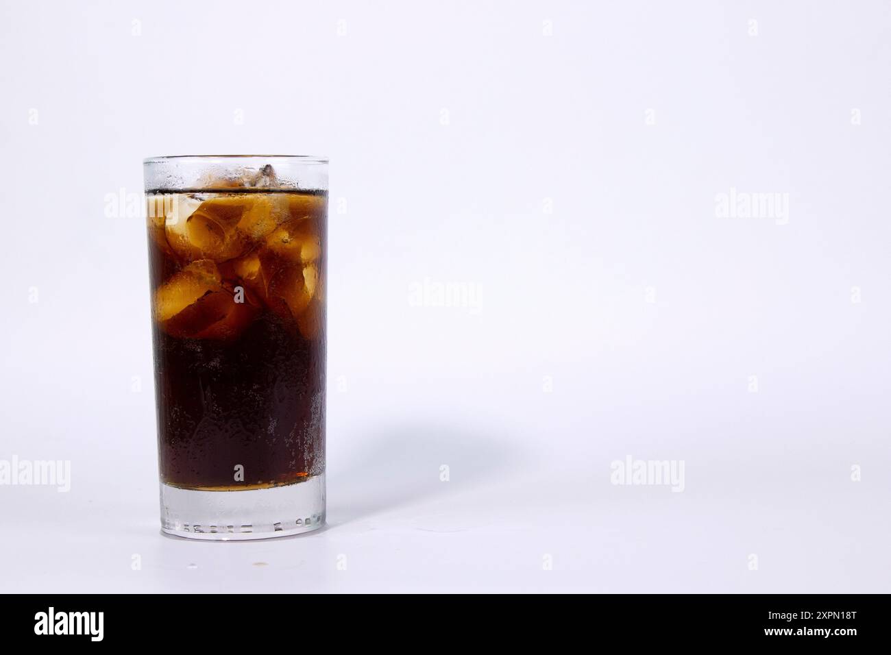 A isolated glass of black cola with ice is filled on white background ...