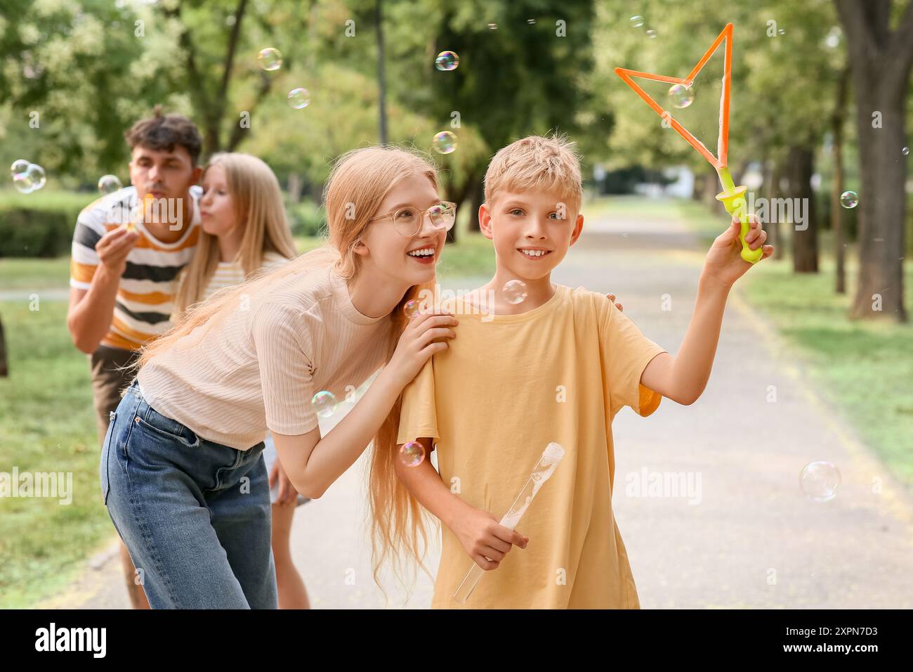 Happy family with cute children blowing soap bubbles in park Stock ...