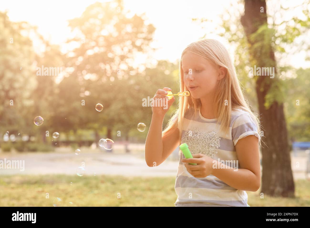 Cute happy little girl blowing soap bubbles in park Stock Photo - Alamy