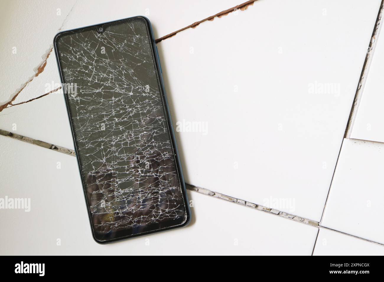 Smartphone with broken screen on the cracked floor Stock Photo