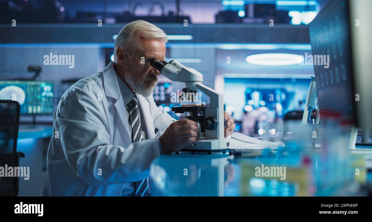 Medical Development Laboratory: Senior Caucasian Male Scientist Using Microscope, Analyzes Petri Dish Sample. Big Pharmaceutical Lab Conducting Biotechnology Research, Developing Innovative Drugs. Stock Photo
