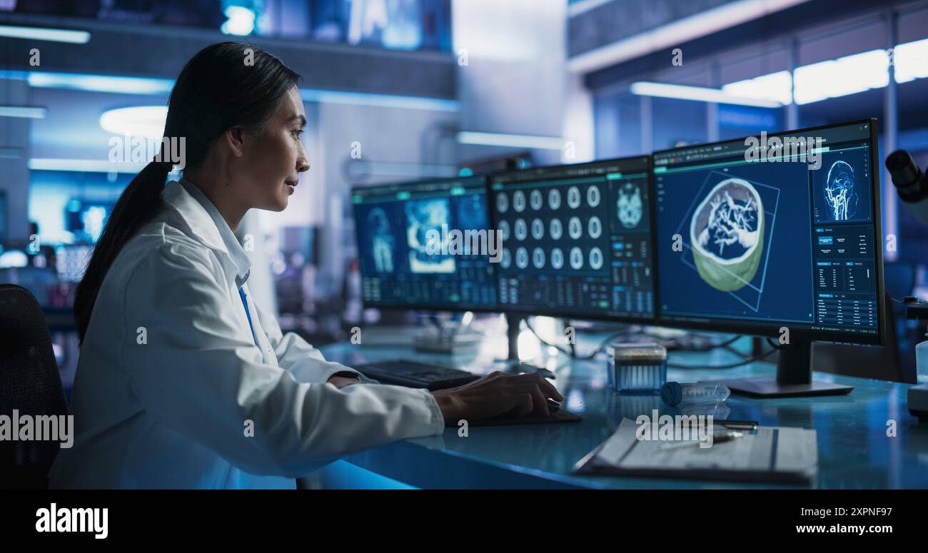 Female Asian Neuroscientist Using Desktop Computer With Human Brain CT ...