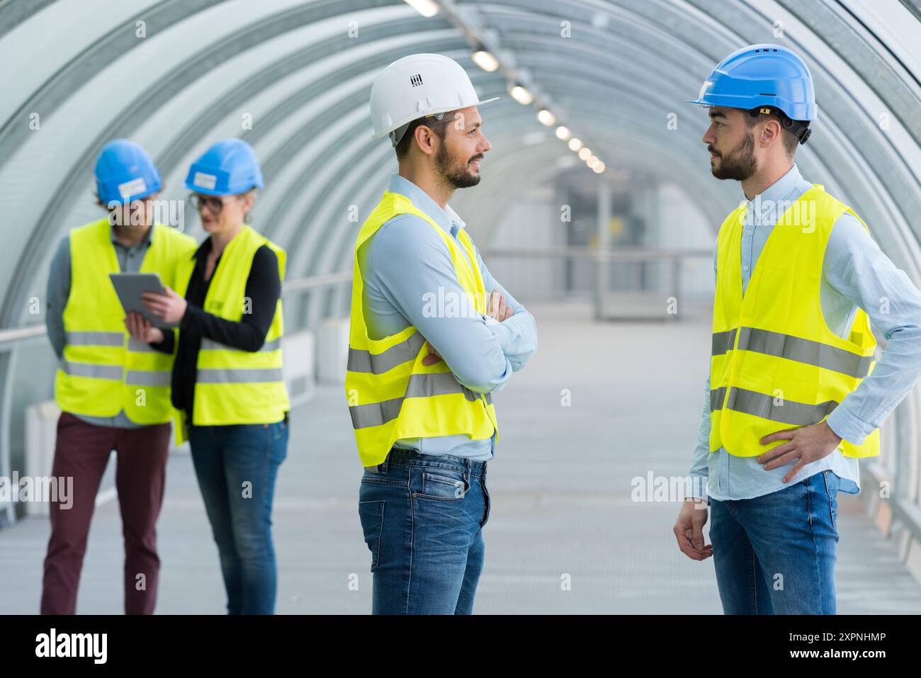 construction workers talking in covered walkway Stock Photo - Alamy
