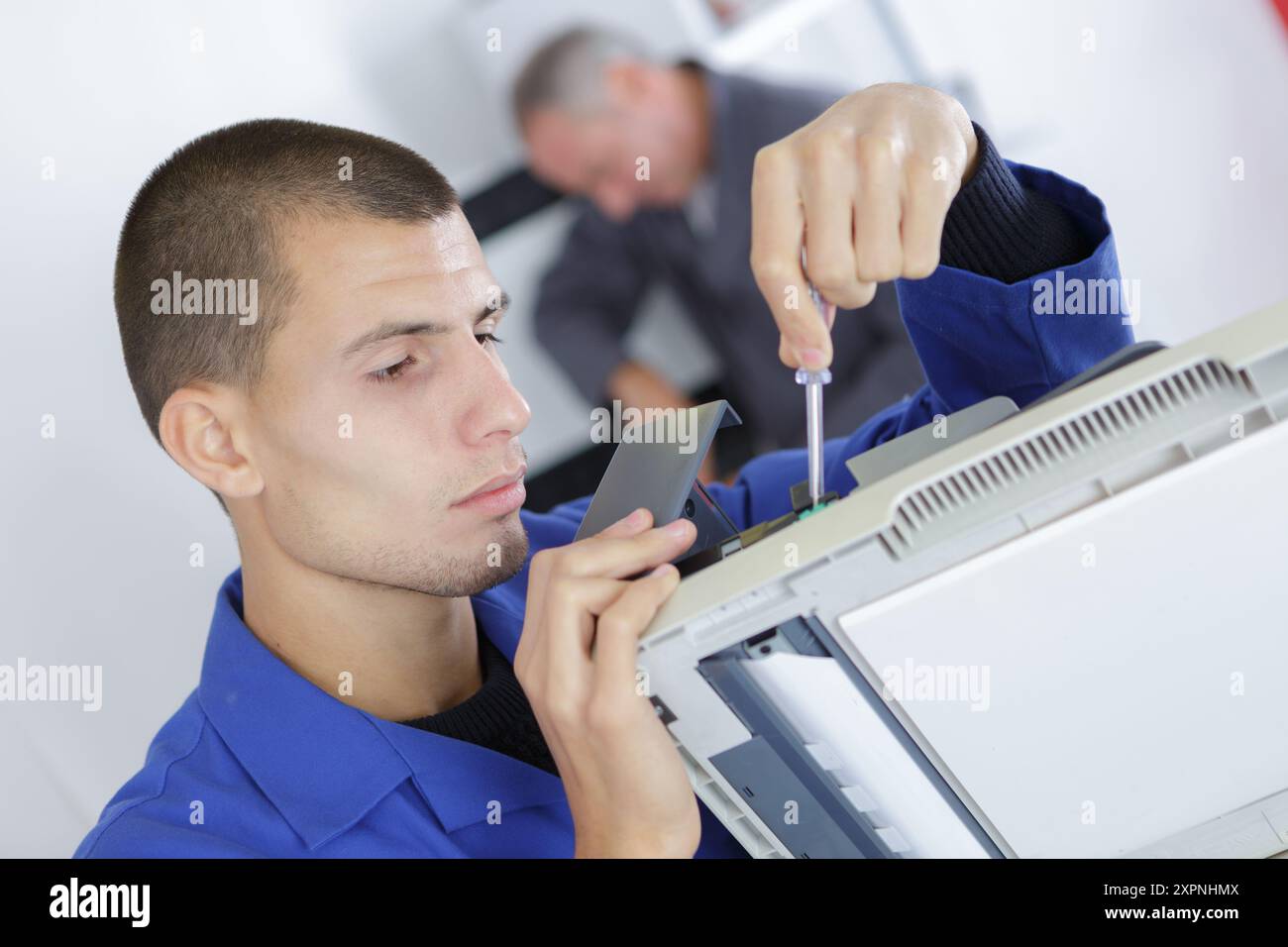young serviceman in overall working on fridge Stock Photo