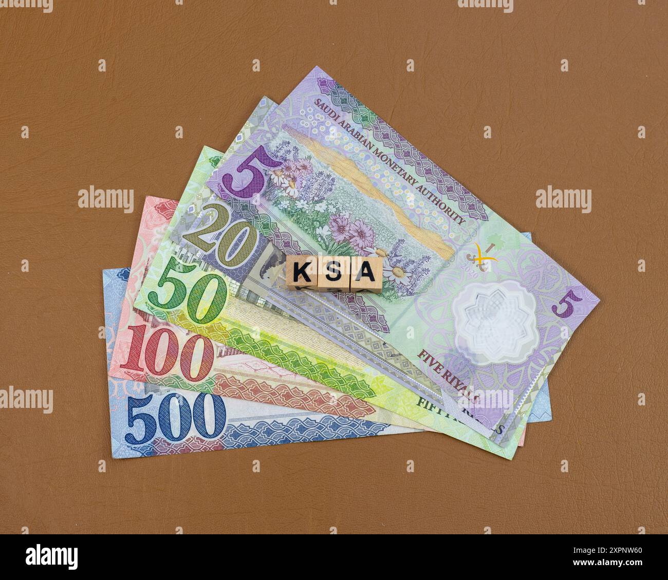 KSA currency notes of 5, 20, 50, 100 and 500 denominations with a KSA word written on wooden cubes blocks Stock Photo