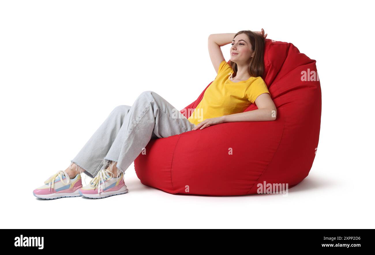 Beautiful young woman sitting on red bean bag chair against white ...