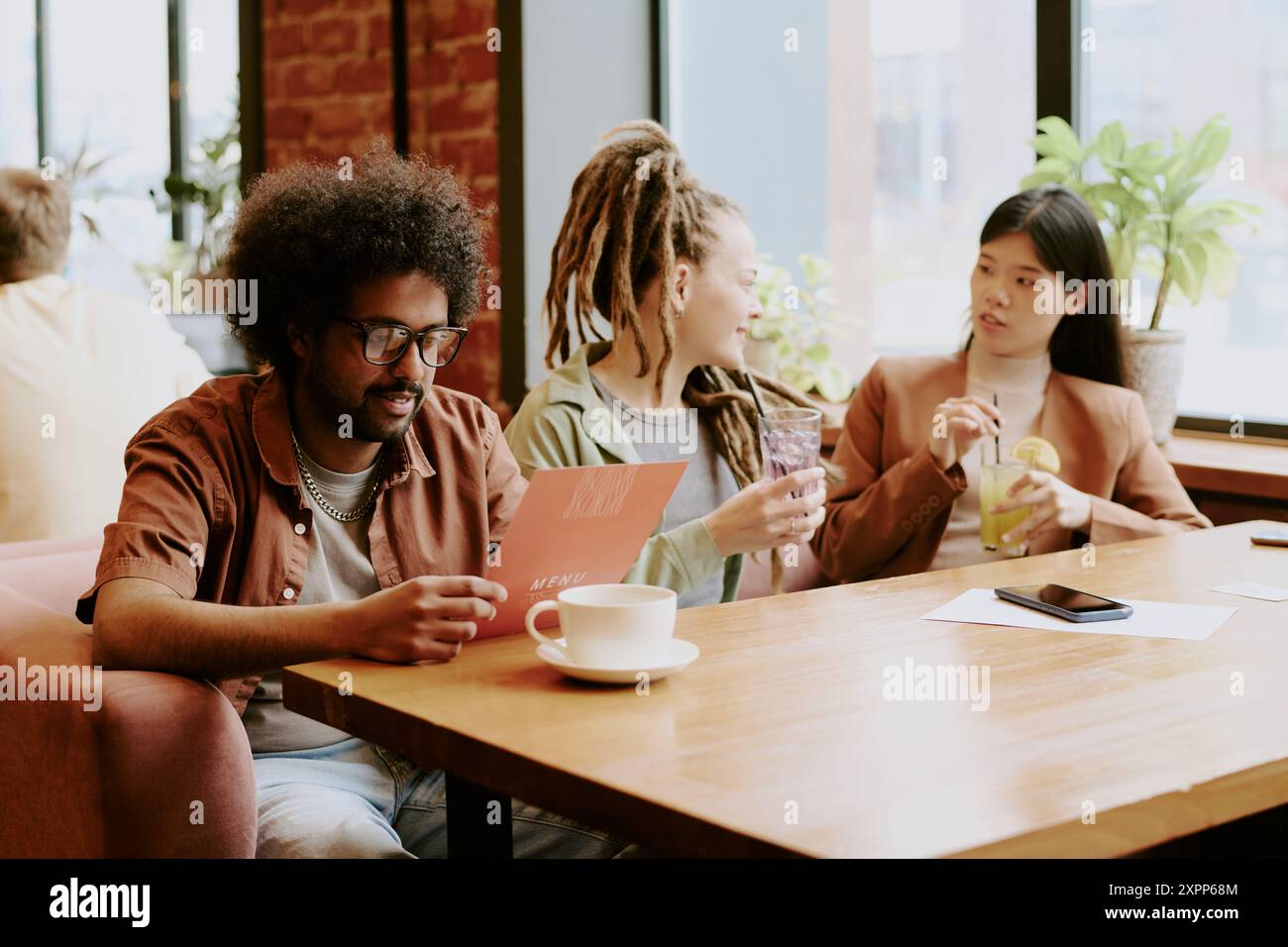 Discussing Menu at Bright Cozy Cafe with Friends Stock Photo - Alamy
