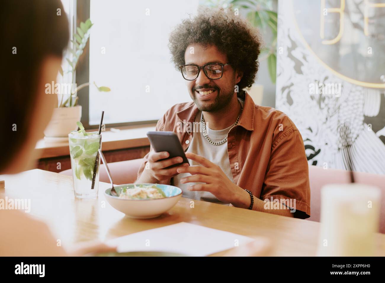 Smiling Young Man Using Smartphone at Restaurant Stock Photo