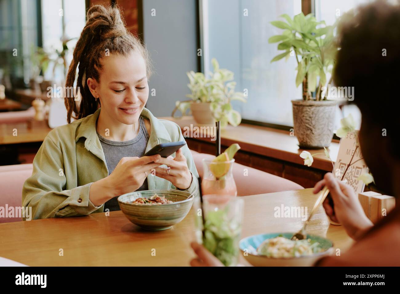 Smiling Woman Using Smartphone in Cozy Restaurant Setting Stock Photo