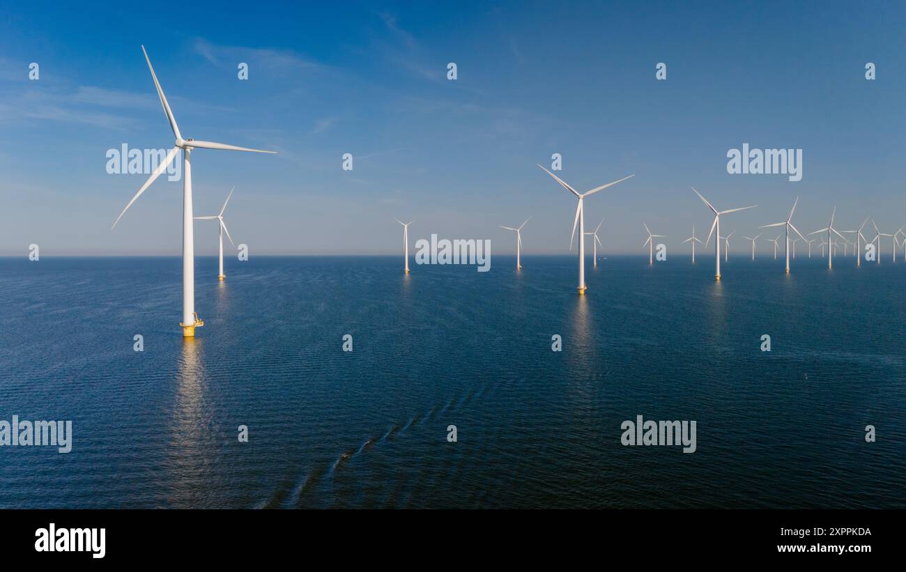 Towering wind turbines at lake Ijsselmeer, harness the gentle sea breeze over expansive waters, showcasing sustainable energy in action. Green energy transition in the Netherlands Stock Photo