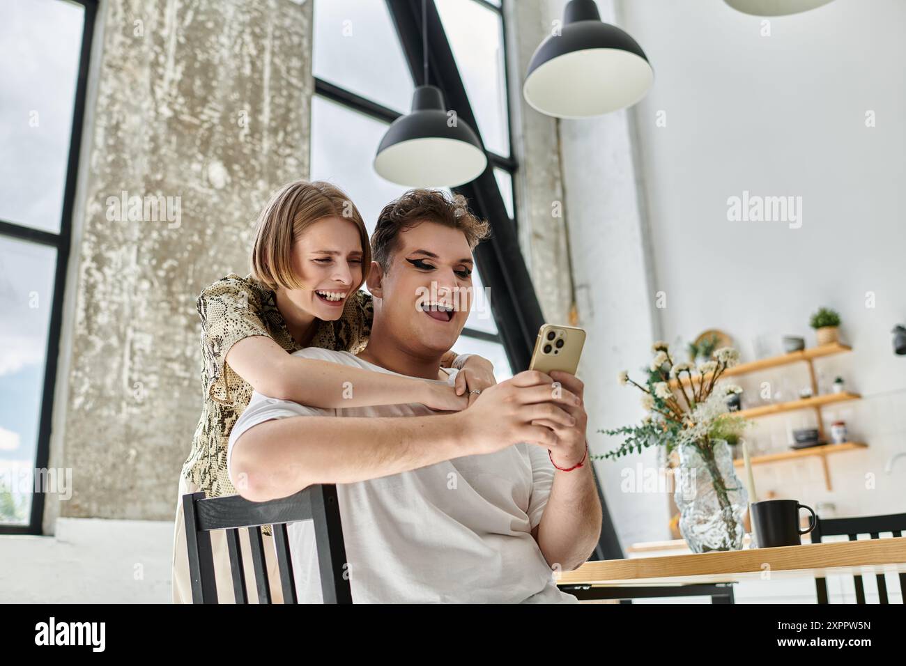 Two friends share laughter while exploring their phones in a cozy ...