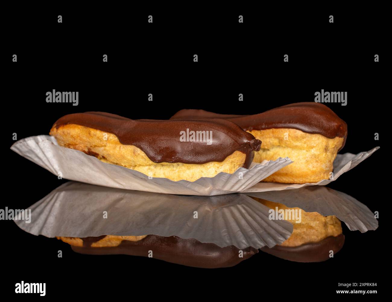 Two eclairs with cream, macro, isolated on a black background. Stock Photo