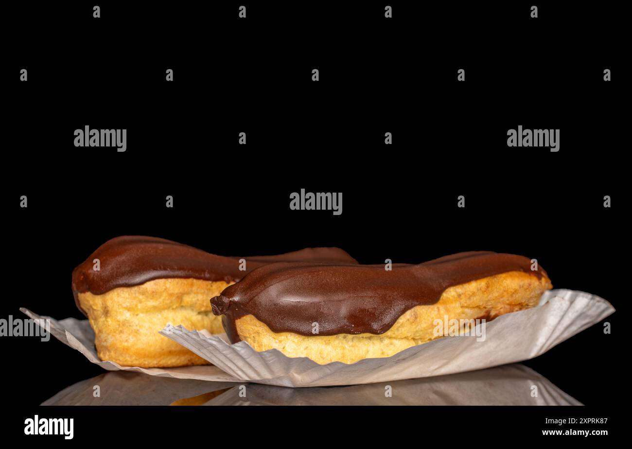 Two eclairs with cream, macro, isolated on a black background. Stock Photo