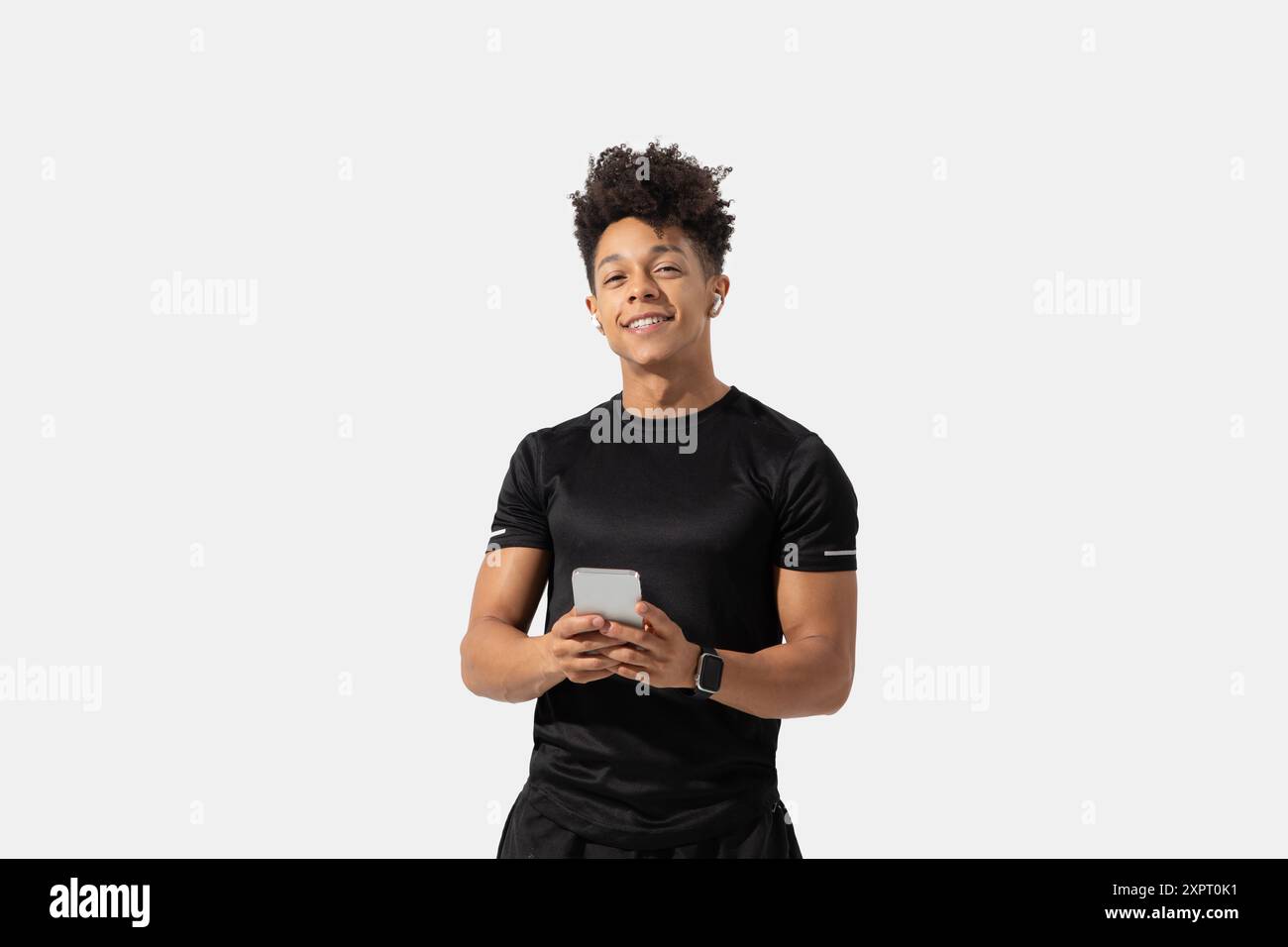 Young Man Smiling While Holding Smartphone in Studio Stock Photo