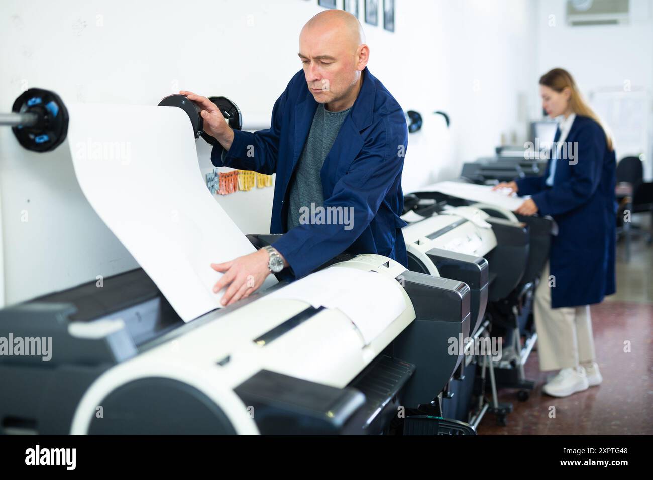 Service man uses plotter and checks functionality in printing shop Stock Photo