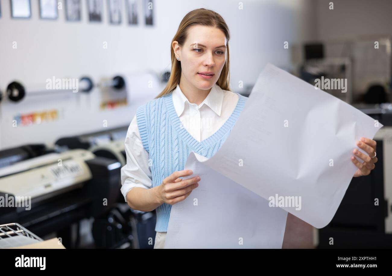 Print worker controlling printing process on modern offset machine in print shop Stock Photo