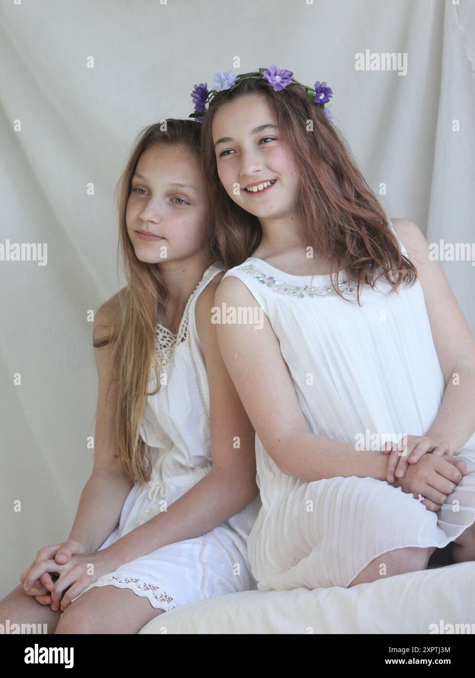 two cheerful preteen girls wearing white dresses on light background ...