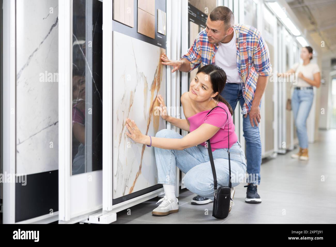 Couple exploring tile samples on sliding display stand in showroom Stock Photo