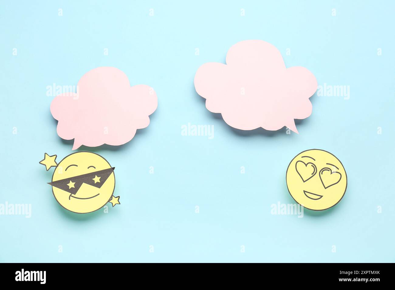 Paper faces with blank speech bubbles on blue background Stock Photo
