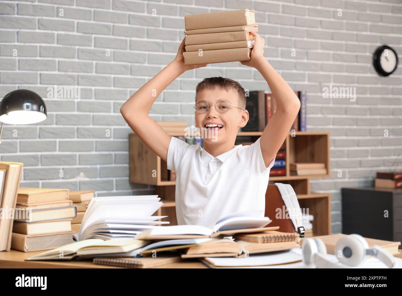 Teenage boy with books at table in library Stock Photo - Alamy