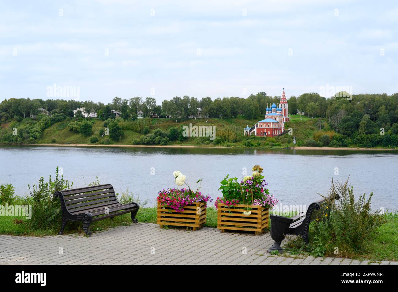 The Volga River embankment with benches and flowers, and a view of the Kazan Transfiguration Church on the other bank, in the evening Stock Photo