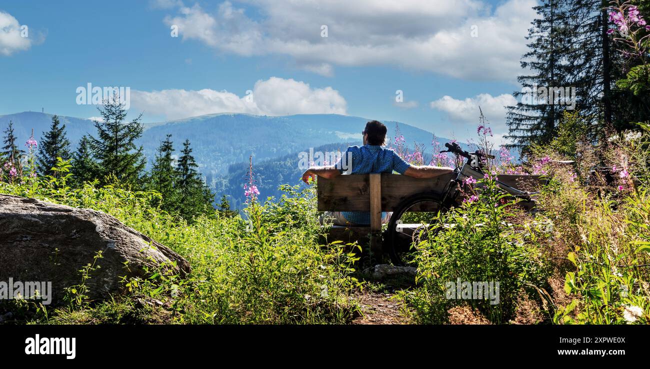 Radfahrer macht Pause auf einer Bank mit Blick auf den Feldberg im Schwarzwald Stock Photo