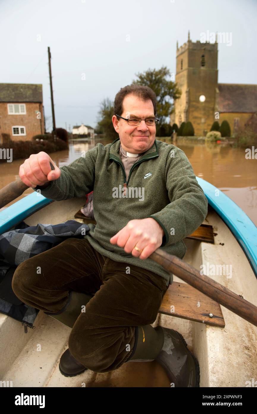 The Revd John Longuet-Higgins negotiates flood water from the River Severn to check on the marooned church of St Michael's and All Angel's at Tirley, Stock Photo