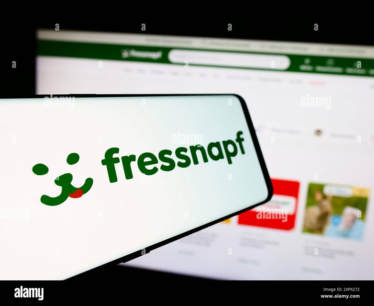 Cellphone with logo of German retail company Fressnapf Holding SE in front of business website. Focus on center-left of phone display. Stock Photo