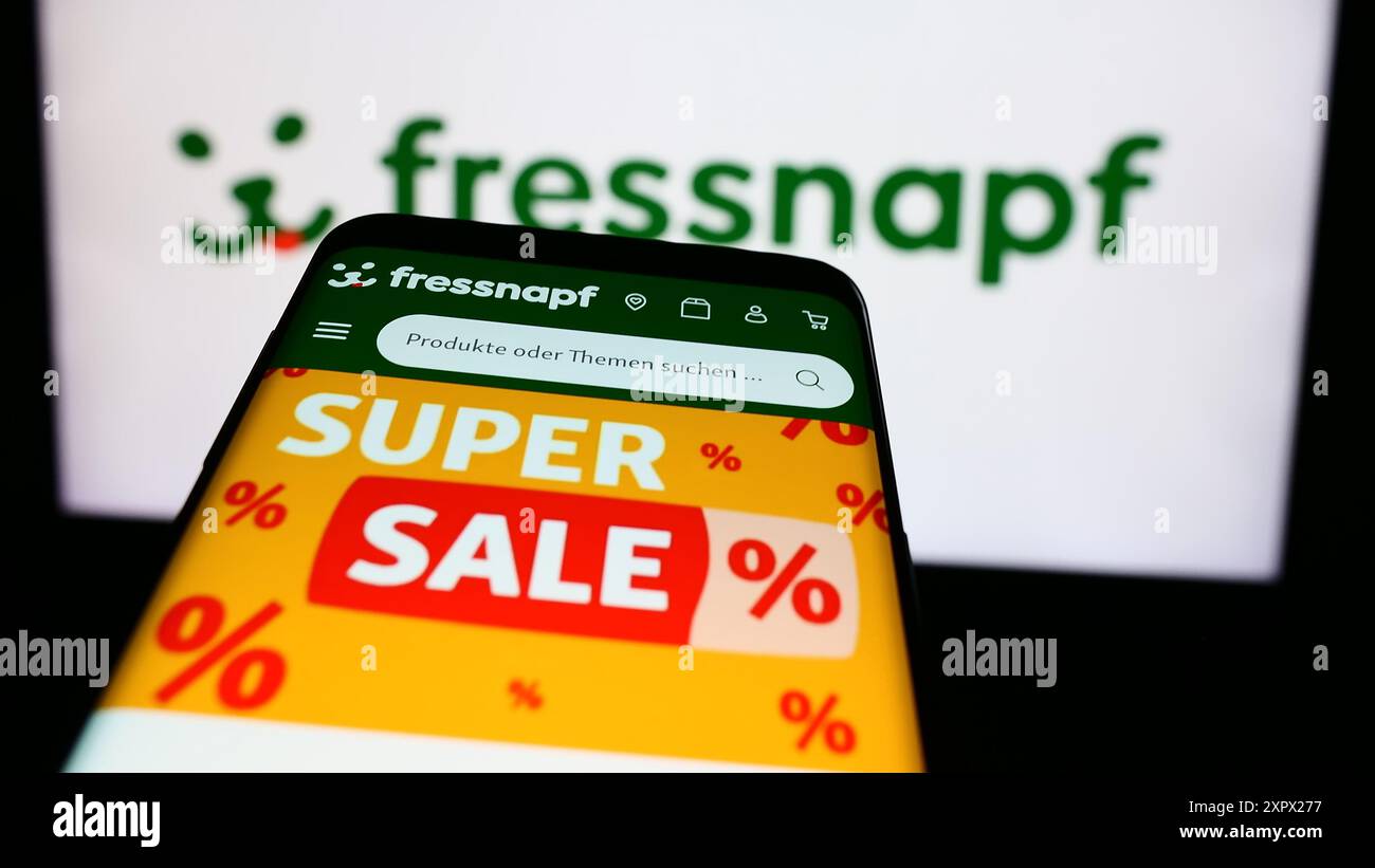Mobile phone with webpage of German retail company Fressnapf Holding SE in front of business logo. Focus on top-left of phone display. Stock Photo