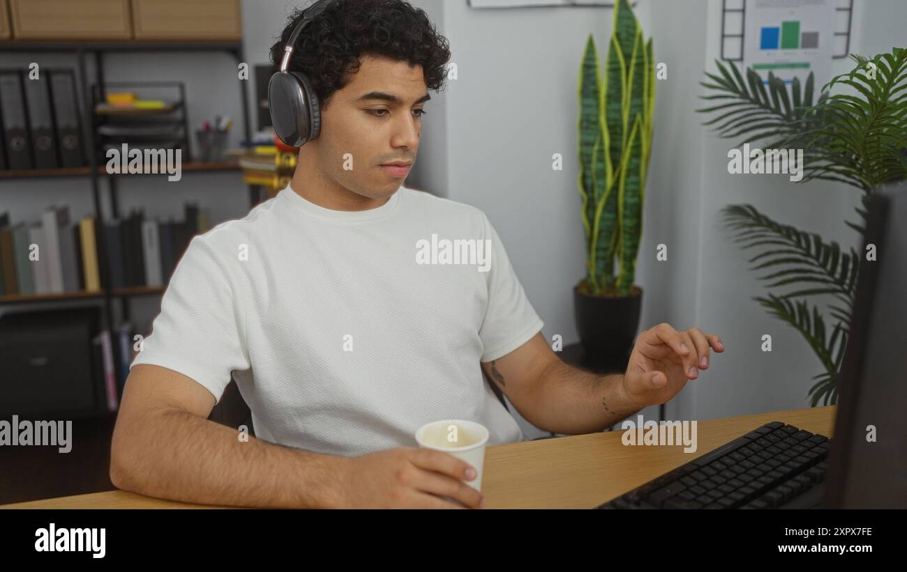 Hispanic Man Using Computer A young hispanic man works intently at a computer in a modern office ...