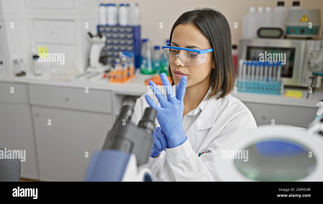 Focused young woman scientist analyzing samples in an urban laboratory setting Stock Photo