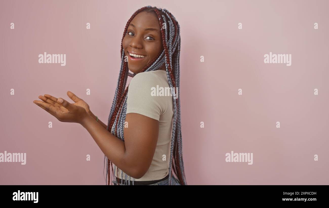 A cheerful african american woman with braids presents against a pink ...