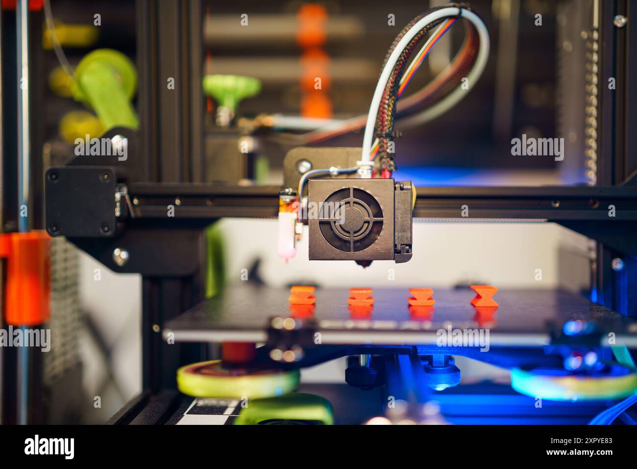 3d printer with printed orange parts. Home lab background Stock Photo