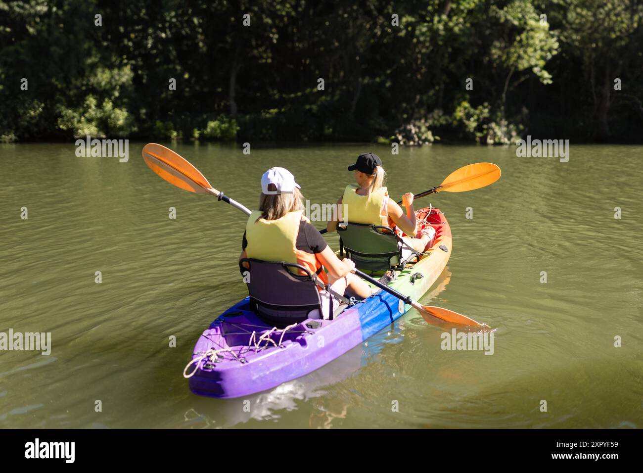 Two young women floating and smiling in a kayak on the river Stock ...