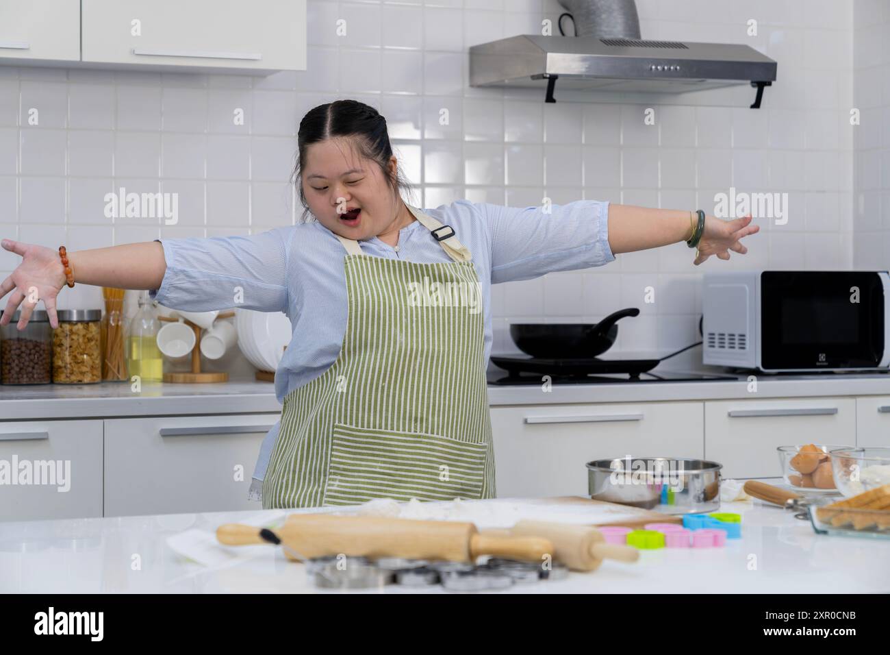 A young girl happily practicing cooking in the kitchen Stock Photo - Alamy