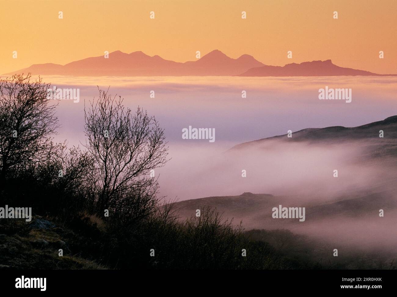 Islands of Rum and Eigg in the Inner Hebrides viewed from Ardnamurchan Peninsular through incoming sea fog at sunset, Argyll, Scotland, May 2002 Stock Photo