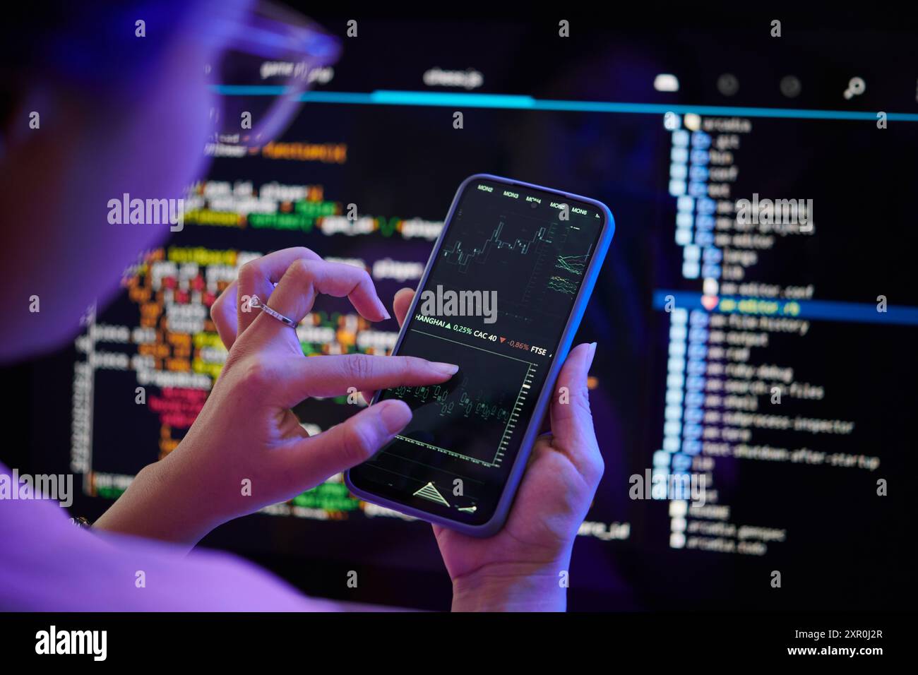Examining Code on Smartphone While Sitting at Desk Stock Photo