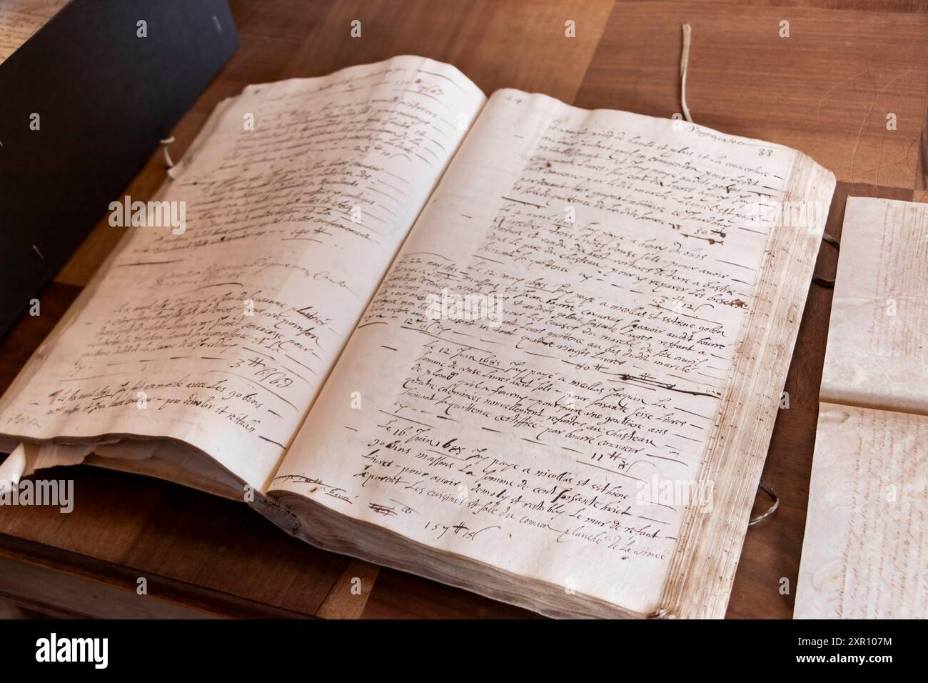 An open vintage manuscript with handwritten text on aged paper, resting on a wooden desk. Stock Photo