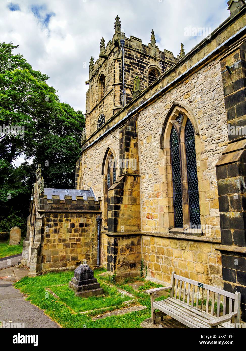 Historic stone church surrounded by lush greenery under a partly cloudy ...