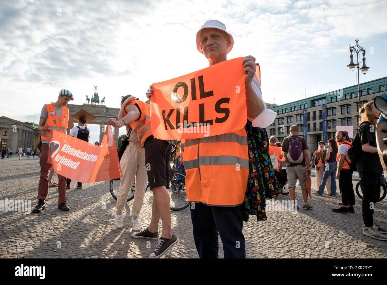 Berlin, Germany. 8th Aug, 2024. Protesters gathered at Berlin's iconic Brandenburg Gate on August 8, 2024, to support members of the climate activist group ''Letzte Generation'' (Last Generation) following a series of police raids earlier in the day. The raids, which took place in several German cities, including Berlin, were conducted as part of an investigation into the activists' involvement in a disruptive protest at Frankfurt Airport on July 25. During that protest, members of the group managed to breach security and occupy the airport's runway, resulting in the cancellation of 250 fligh Stock Photo