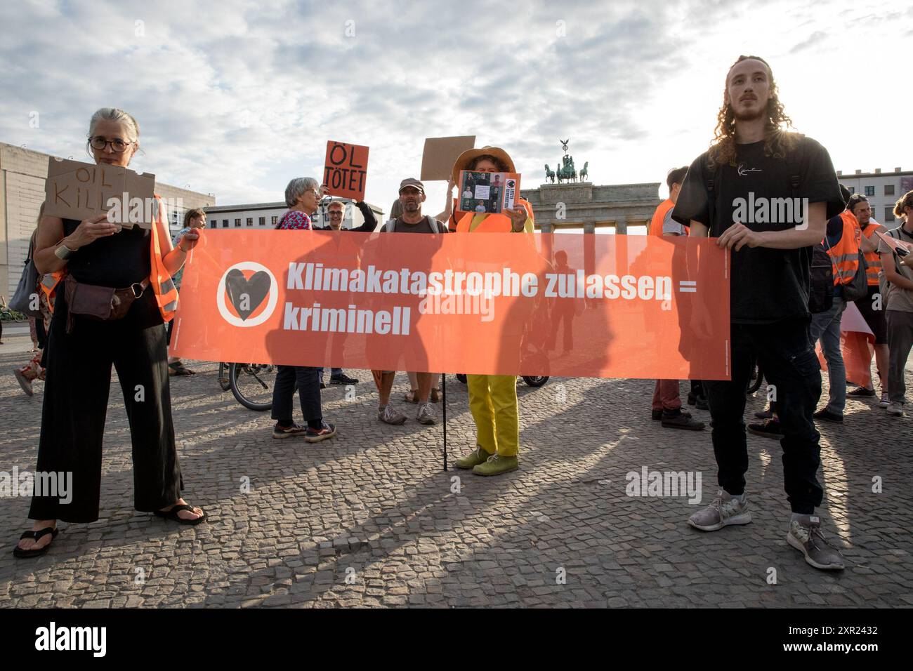 Protesters gathered at Berlin's iconic Brandenburg Gate on August 8, 2024, to support members of the climate activist group 'Letzte Generation' (Last Generation) following a series of police raids earlier in the day. The raids, which took place in several German cities, including Berlin, were conducted as part of an investigation into the activists' involvement in a disruptive protest at Frankfurt Airport on July 25. During that protest, members of the group managed to breach security and occupy the airport's runway, resulting in the cancellation of 250 flights and affecting over 30,000 passen Stock Photo