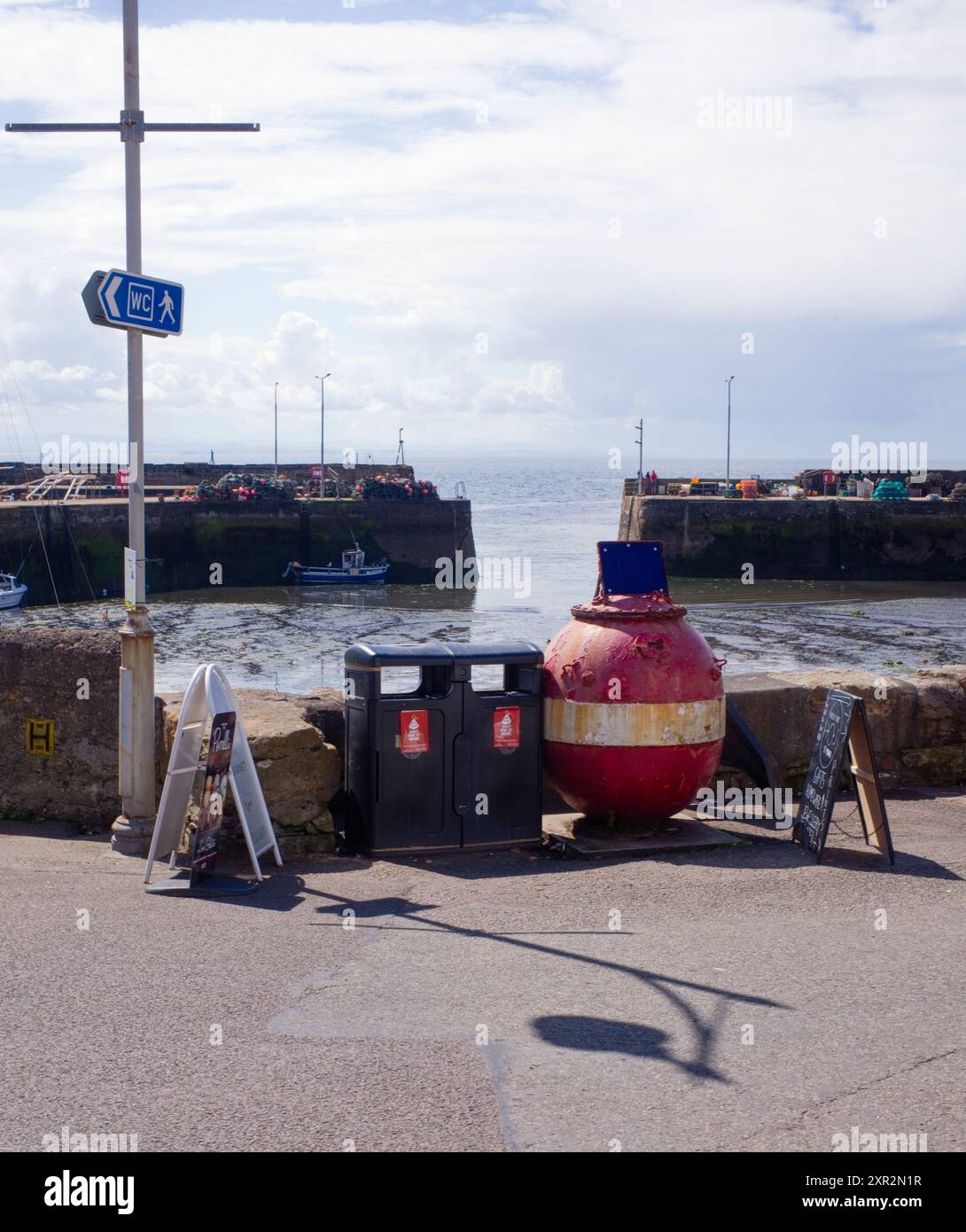 Sea mine amongst a boards, bins and other urban clutter at St Monans, Scotland Stock Photo