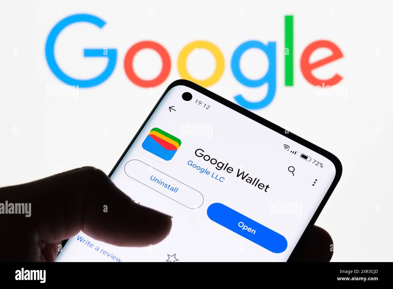 Close-up of a smartphone screen displaying Google Wallet app with Google logo in the background, illustrating the connection between Google Wallet and Stock Photo