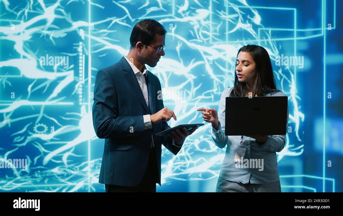 Software developers use neural networks modeled after human brain to solve complex problems. IT specialists in high tech workspace using artificial intelligence to look at data Stock Photo