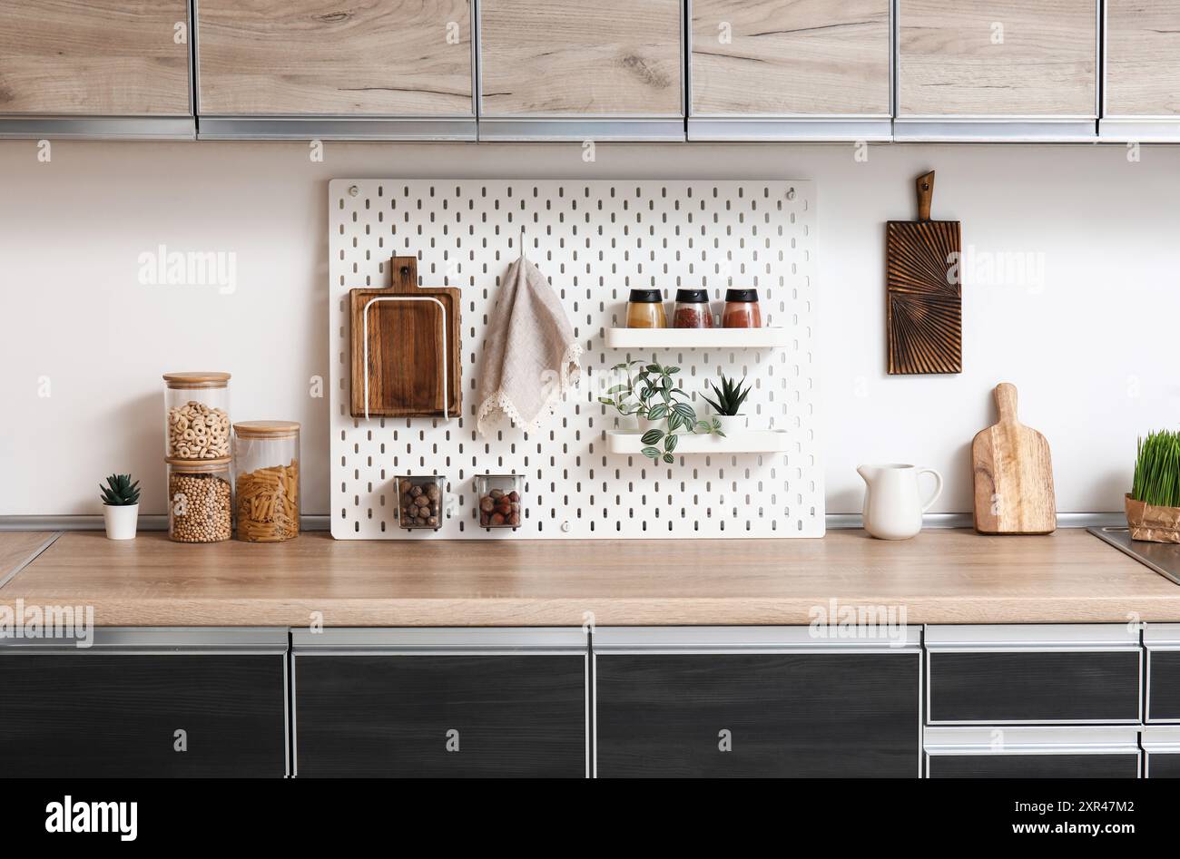Interior of stylish kitchen with black counters, peg boards and white ...