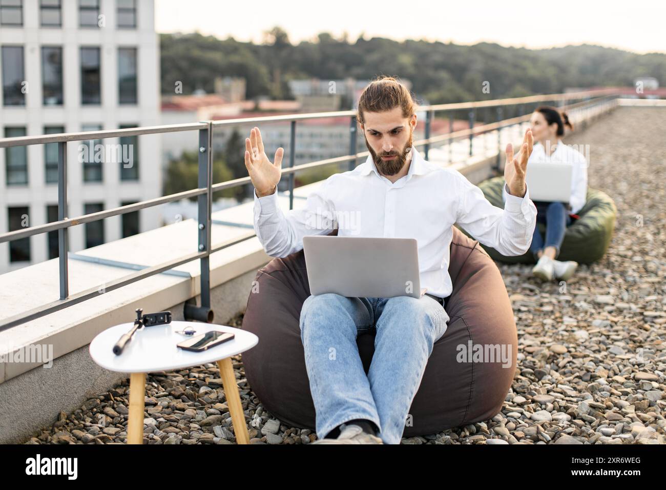 Young professionals working remotely on rooftop with laptops Stock Photo