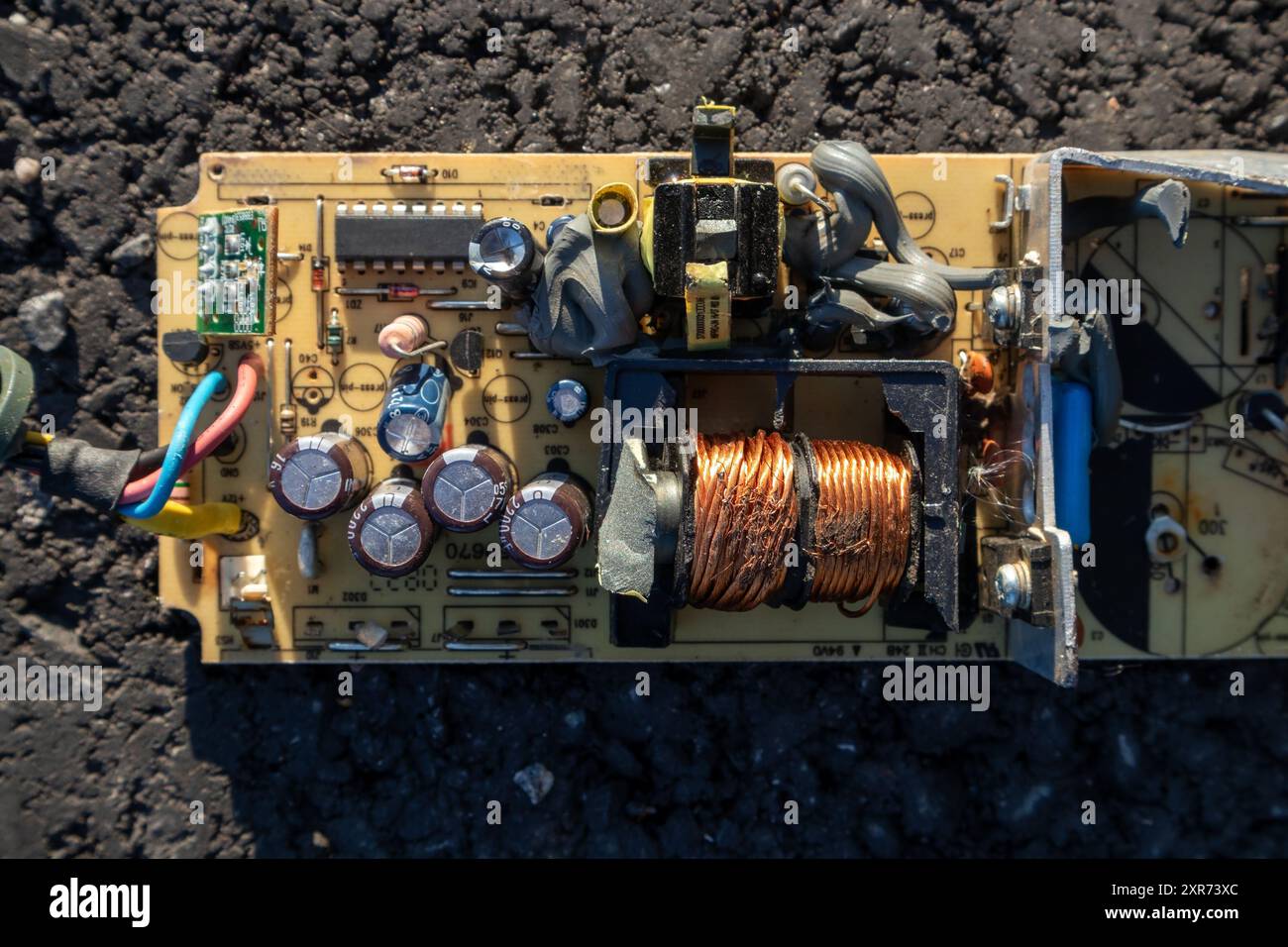 broken electronics board on asphalt outdoors in sunlight Stock Photo