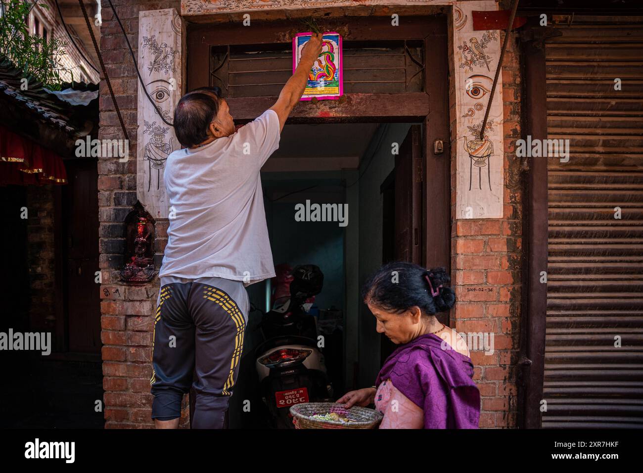 Bhaktapur, Bagmati, Nepal. 9th Aug, 2024. A man worship serpent deity(Snake) at the main door step of the house with cotton lamp after offerings during Nag Panchami Festival. People on this day stick the poster of serpent deity(snake) on the main door step of the house, clean nearest local pond and worship snake gods, also called the Nagas during Nag Panchami. (Credit Image: © Amit Machamasi/ZUMA Press Wire) EDITORIAL USAGE ONLY! Not for Commercial USAGE! Credit: ZUMA Press, Inc./Alamy Live News Stock Photo