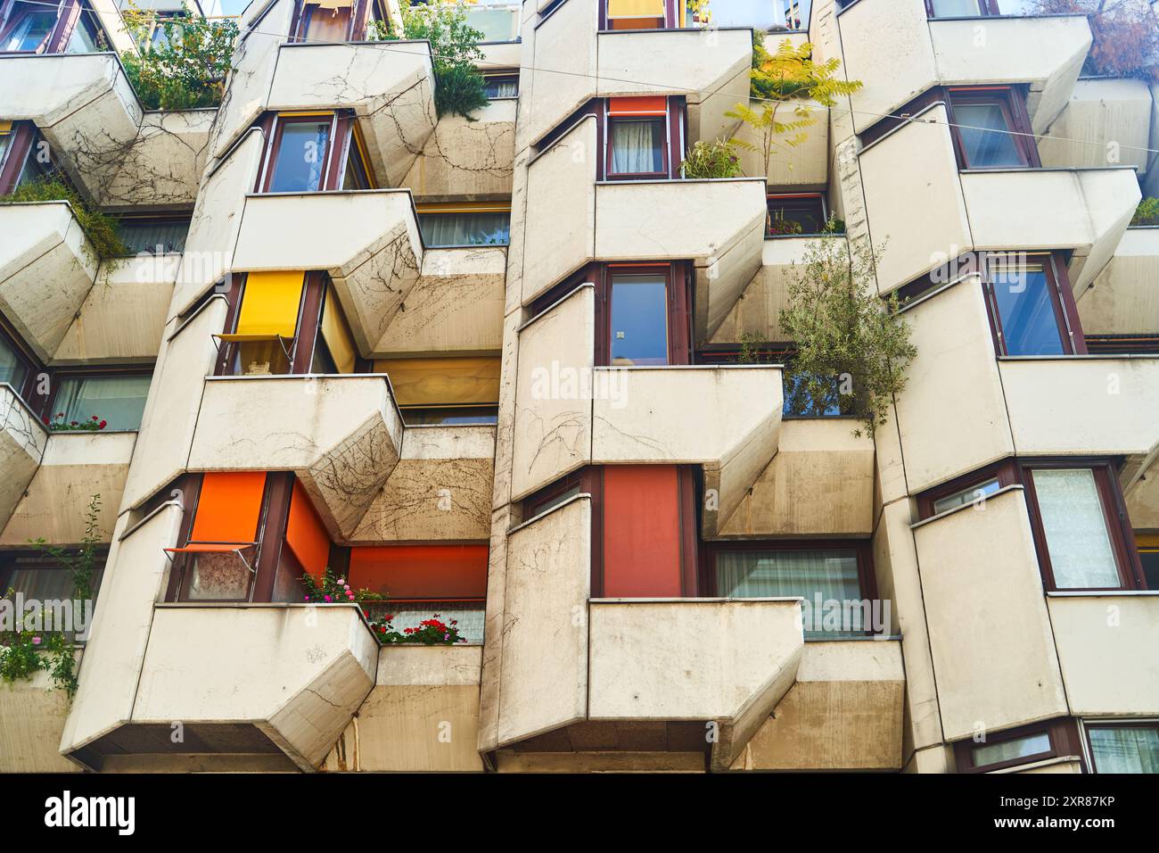 Image showcasing Urban apartment building with many windows, balconies, and a lush ...