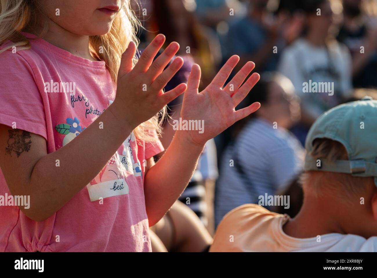 Lublin, Poland, July 26 2024 children in the audience of a street circus festival ('Carnavl Sztukmistrzow') clap their hands at sunset Stock Photo